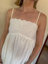 Vestido blanco de algodón con breteles finos y aplique bordado en el busto.