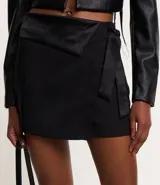 Short pollera corto de crepé negro con detalle satinado asimétrico y lazo lateral.