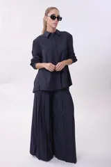 Pantalón palazzo plisado color azul marino, de tiro alto con bolsillos laterales y cierre frontal con botón.