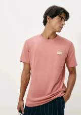 Camiseta de manga corta color salmón, con cuello redondo y pequeño logo estampado en el pecho.