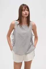 Blusa sin mangas con estampado a rayas verticales en tonos blanco, azul y verde. Presenta cuello redondo y lazos laterales.