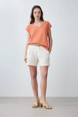 Remera color durazno con escote en V y detalle de vainillas en los laterales. De manga corta y corte recto.