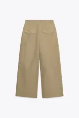 Pantalón color beige de tiro medio con trabillas, bolsillos laterales, de plastrón en pierna y detalle de solapas en espalda. Detalle de pinzas en delantero y cierre frontal con cremallera y ganchos metálicos.