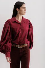 Camisa color borgoña con cuello clásico, abotonada al frente y mangas largas abullonadas.