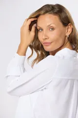 Blusa tipo camisa blanca con estampado de pequeñas flores negras, manga larga, botones nacarados ocultos con cartera y doble capa en el frente para evitar transparencias.