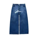 Pantalón de jean azul desgastado, corte mega baggy, con estampa serigrafiada en la pierna y botones personalizados.