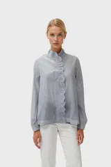 Camisa celeste claro con cuello mao y volados frontales, de corte holgado y manga larga.