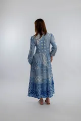 Vestido midi de corte amplio con estampado floral en tonos azules y blancos. Tiene cuello mao con botones y mangas largas abullonadas.