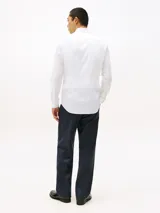 Camisa blanca de popelina con tecnología flex, de corte slim, manga larga y cuello abotonado. Incluye logo de Tommy Hilfiger bordado en el pecho.