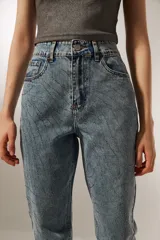 Pantalón de jean celeste con diseño de líneas curvas bordadas y strass. Corte recto y tiro alto.