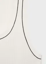 Musculosa blanca de punto canalé con ribete negro en cuello y sisas.