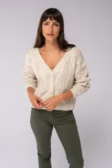 Saco color beige de tejido de punto trenzado, con escote en V y cierre frontal con botones marrones.