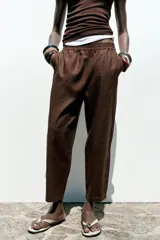 Pantalón bombacho color beige de lino, con cintura elástica, bolsillos frontales y bolsillos de parche en la espalda.