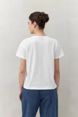Remera blanca de manga corta con estampado floral en tonos dorados en el frente.