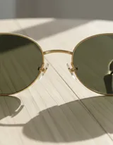 Lentes de sol ovalados con montura delgada dorada y patillas gruesas con estampado carey. Lentes polarizadas verdes con protección UV400.