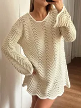 Vestido corto tejido en algodón y lurex color crudo, con punto pavo real, manga larga y escote en la espalda.