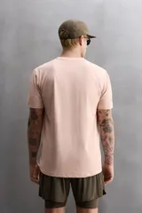 Remera deportiva color rosa claro, de tejido técnico ligero y elástico con estructura. Cuello redondo, manga corta, costuras planas y logo estampado.