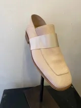 Mocasín de cuero color beige con textura reptil, detalle de tira ancha horizontal y suela de madera.