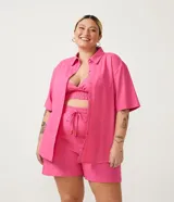 Conjunto de lino color rosa compuesto por un top estilo corpiño con elástico en la parte inferior, shorts con cordón ajustable y camisa de manga corta con botones.