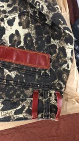 Pantalón de jean con estampado animal print en tonos beige y negro, de corte ancho y tiro medio. Presenta detalles de cuero bordó en la pretina y los bolsillos.