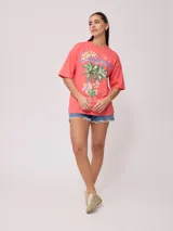 Remera color crudo de corte oversized con estampado de palmeras, flores y texto 'California' y 'Rusty Tribe'.