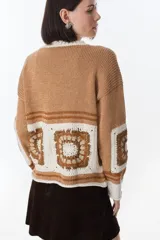 Sweater azul con cuello redondo y diseño de cuadrados de crochet en la parte inferior.