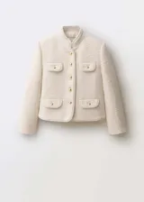 Chaqueta de tweed color crudo con cuello mao, cuatro bolsillos frontales con solapa y botones dorados.