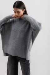 Sweater gris de punto con cuello alto y diseño de líneas horizontales en relieve.