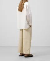 Camisa blanca de algodón con finas rayas verticales. Tiene cuello solapa, cierre con botones, manga larga con puño, bolsillo en el pecho y canesú en la espalda.