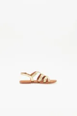 Sandalias bajas doradas con tiras finas cruzadas y hebilla en el tobillo.