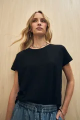 Remera de manga corta color gris claro, confeccionada en algodón con textura liviana y suave al tacto. Presenta costuras decorativas en los laterales y mangas con pequeño doblez.