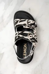Sandalias con plataforma de goma negra y tiras de pelo de vaca con hebillas plateadas.