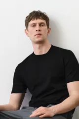 Remera negra de punto fino, con cuello redondo y mangas cortas. Corte ajustado.