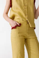 Pantalón de jean azul oscuro, de corte acampanado, con bolsillos delanteros con detalle de volados.