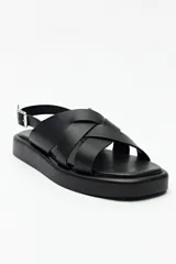 Sandalias negras de símil cuero con agarre ajustable en el talón y capellada entrelazada. Plataforma de 3 cm de alto.