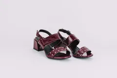 Sandalias de cuero con estampado animal print de vaca en blanco y negro, con detalles de tachas plateadas. Tienen correa trasera con hebilla y taco cuadrado de 5 cm.