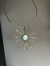 Gargantilla dorada con dije en forma de sol con centro de nácar.