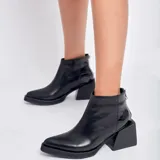 Botines negros de cuero vacuno con detalle de cuero con textura de cocodrilo en el talón y cierre dorado. Taco cuadrado de madera con folia de cuero de 5cm y entre suela de goma de 1,5cm.