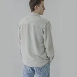 Camisa celeste de pana con corte oversize, cuello clásico, cierre frontal con botones, dos bolsillos con solapa en el pecho y mangas largas con puños abotonados.