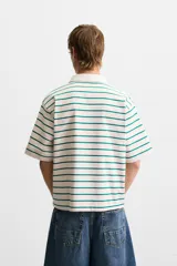 Polo de hombre corte relaxed fit, con cuello solapa y cierre frontal de botonadura. Diseño a rayas horizontales color verde sobre fondo blanco.