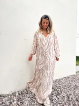 Vestido largo con estampado de cebra en tonos habano y crudo, corte amplio, cuello camisero y mangas largas.