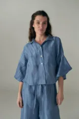 Conjunto de camisa y pantalón celeste con textura arrugada. La camisa es crop con cuello clásico y mangas cortas. El pantalón es de corte ancho con cintura elastizada y cordón ajustable.