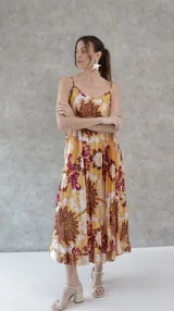 Vestido largo de seda plisada estampada con flores grandes en tonos marrón, amarillo y violeta. Diseño de solera con tirantes finos.