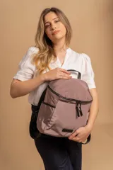 Mochila urbana de diseño compacto, color violeta/malva, con acabado ligeramente brillante. Presenta un compartimento principal con doble cierre superior y bolsillos laterales con cierre.