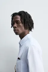 Camisa de algodón color celeste claro, corte regular fit, con cuello abotonado (button-down), manga larga con puño abotonado y bolsillo de parche en el pecho izquierdo.