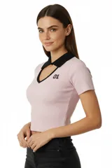 Remera corta de punto canalé color rosa claro, con cuello polo negro con escote en V y detalle de número bordado en el pecho.