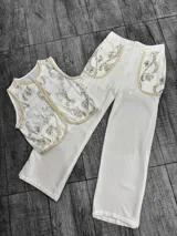 Conjunto de chaleco y pantalón color crudo con bordados de lentejuelas plateadas. El chaleco es sin mangas y el pantalón es de corte recto.