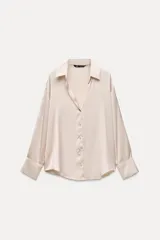 Camisa color beige de cuello solapa, escote pico y manga larga. Cierre frontal con botones.