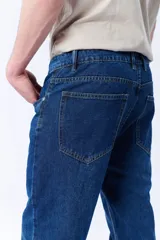 Pantalón de jean azul oscuro, corte slim fit, tiro medio y bolsillos delanteros y traseros.