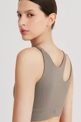 Top deportivo asimétrico color gris topo, realizado en tela doble y cintura elástica para mayor compresión y sujeción.